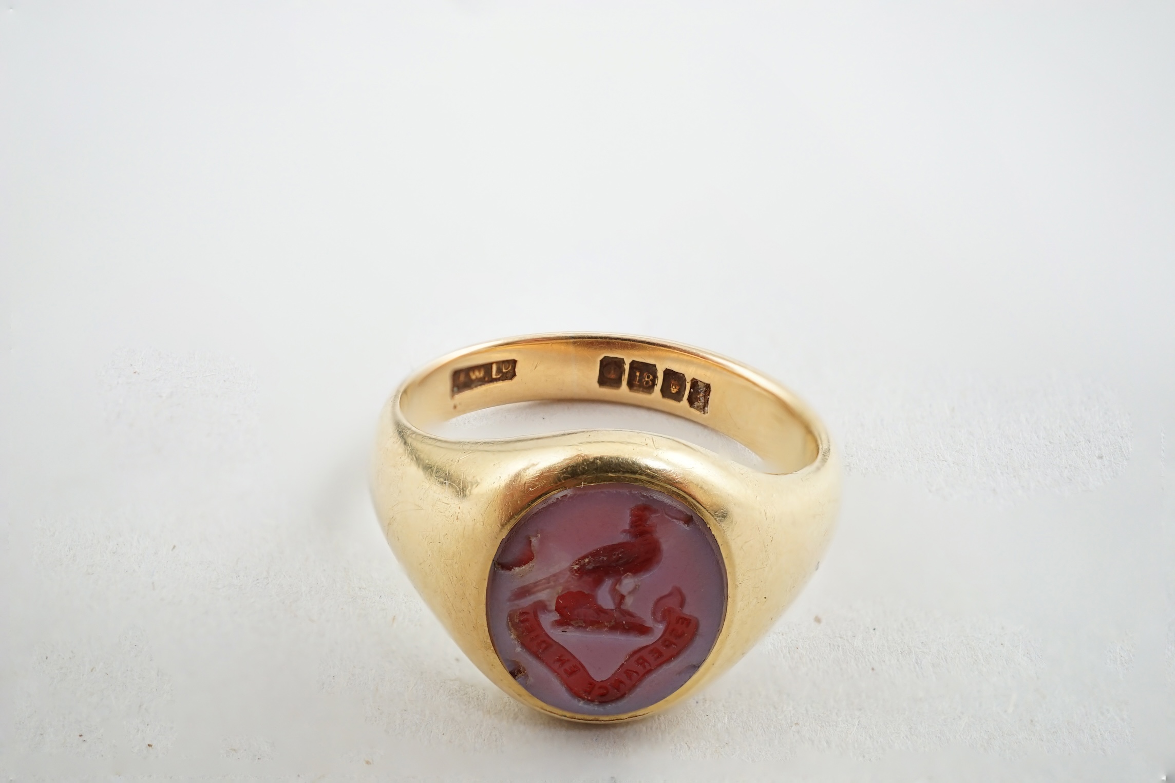 A George V 18ct gold and sardonyx set signet ring, the oval stone carved with family crest